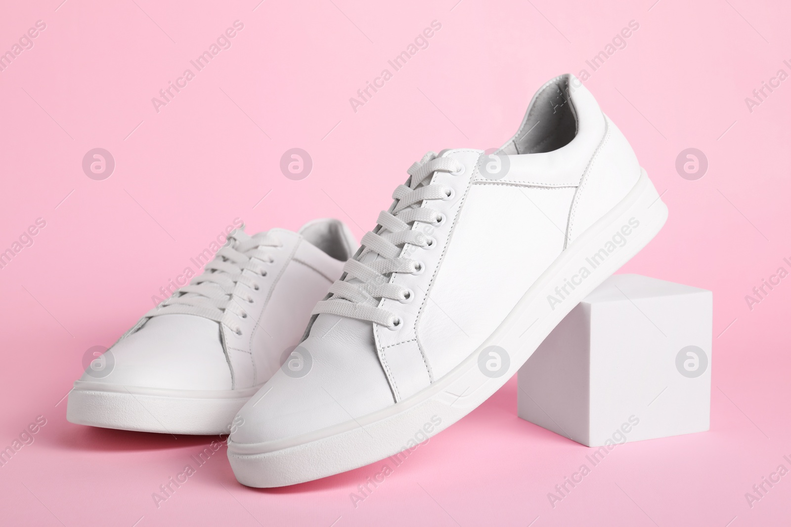 Photo of Pair of stylish white sneakers on pink background