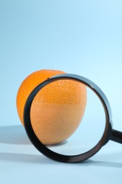 Photo of Cellulite problem. Zoomed orange peel on light blue background, view through magnifying glass. Space for text