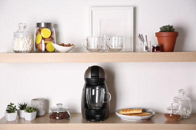 Photo of Modern coffeemaker on wooden table near white wall