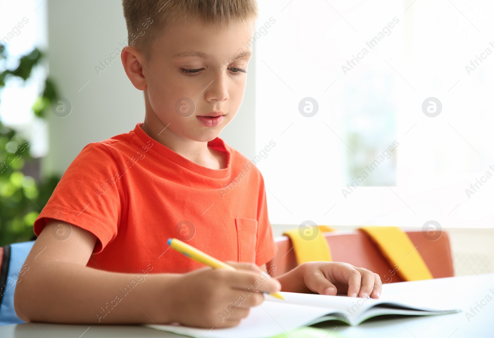 Photo of Cute little child doing assignment at desk in classroom. Elementary school