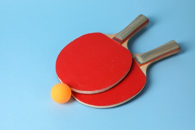 Photo of Ping pong ball and rackets on light blue background