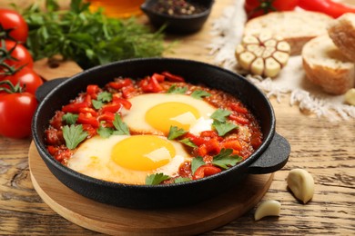 Photo of Delicious Shakshuka in pan on wooden table