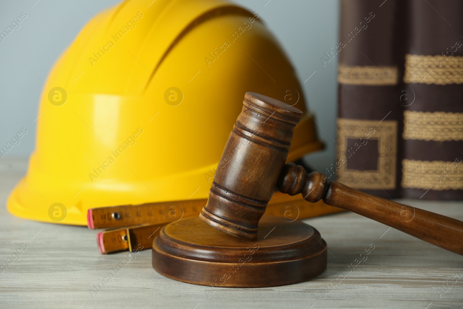 Photo of Construction and land law concepts. Judge gavel, protective helmet, ruler with books on wooden table