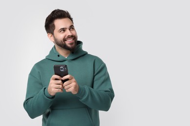 Photo of Happy young man using smartphone on white background, space for text