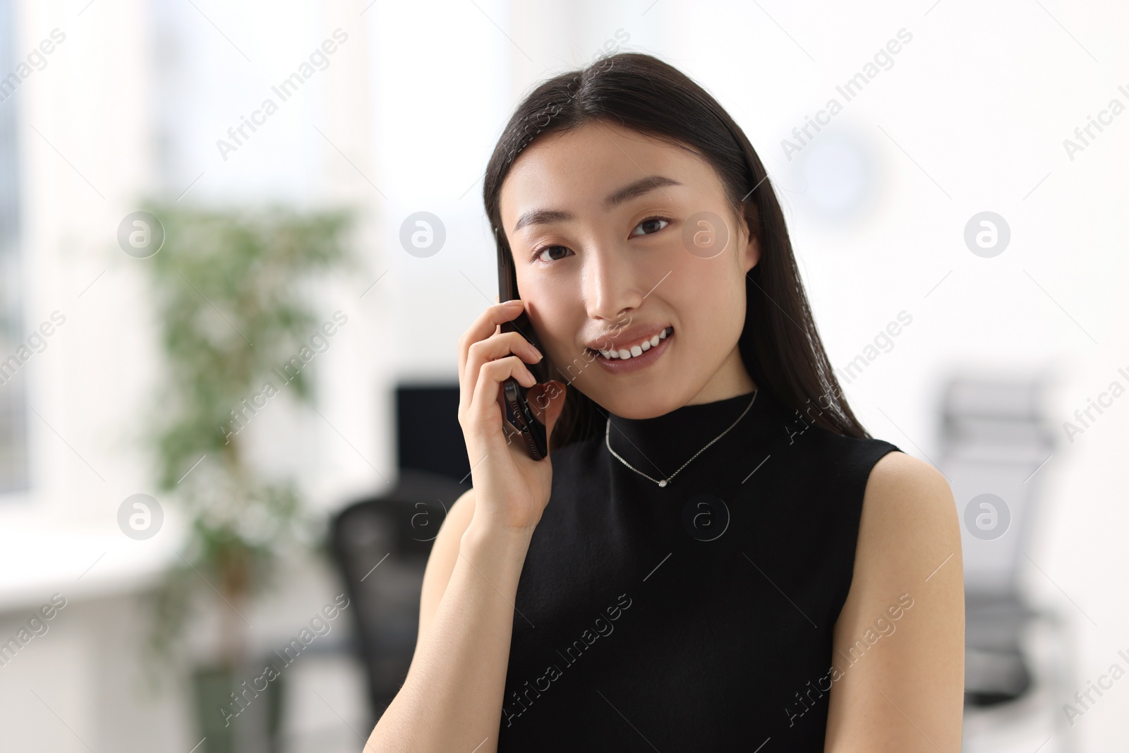 Photo of Portrait of smiling businesswoman talking on smartphone in office