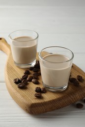 Photo of Coffee cream liqueur in glasses and beans on white wooden table