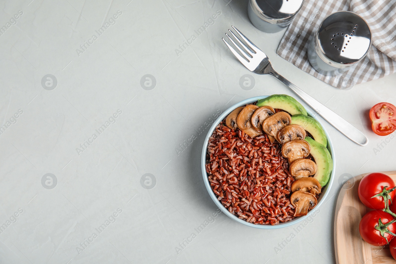 Photo of Bowl of brown rice with mushrooms and avocado on table, flat lay. Space for text