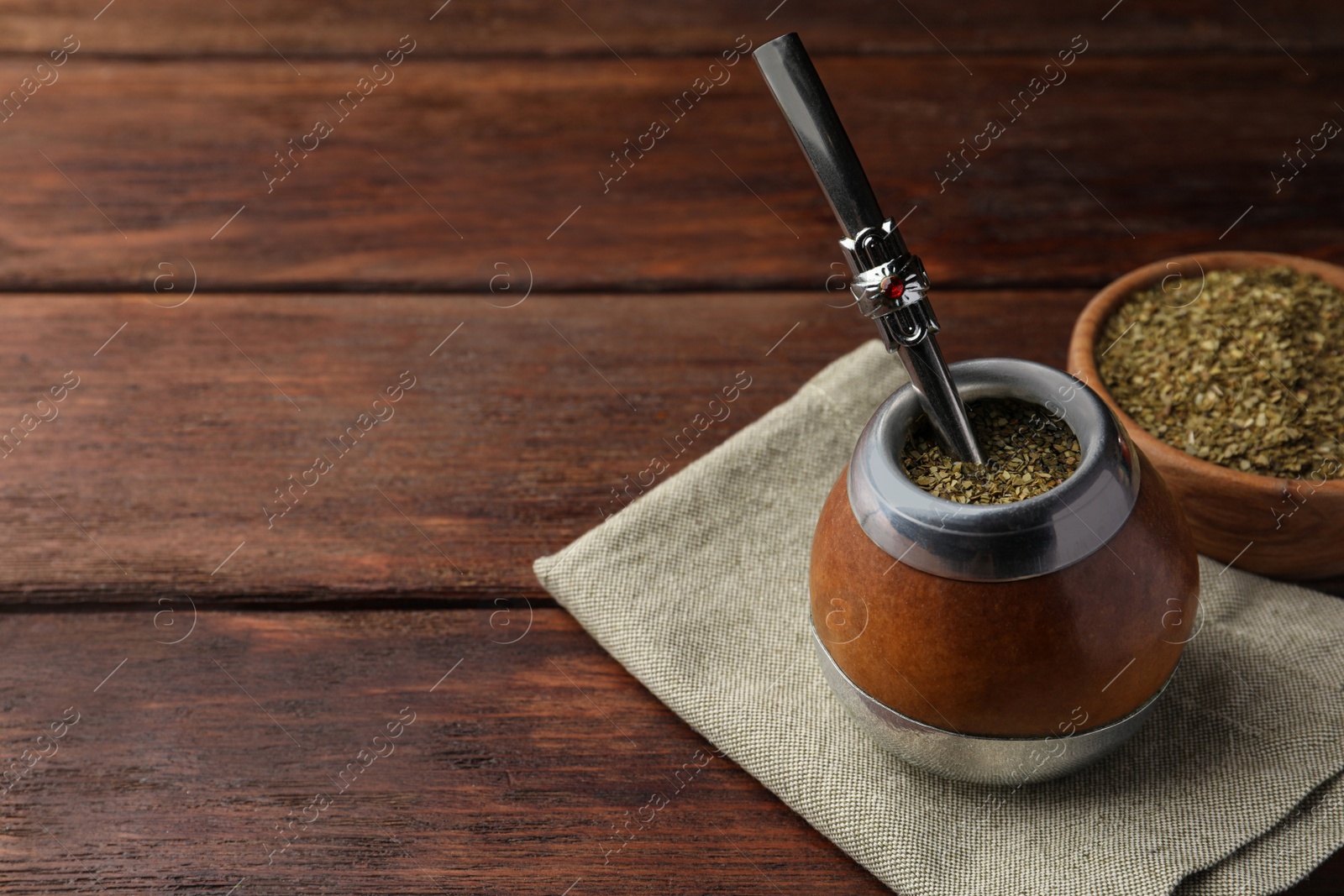 Photo of Calabash with mate tea and bombilla on wooden table. Space for text