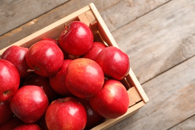 Wooden crate with fresh red apples on table