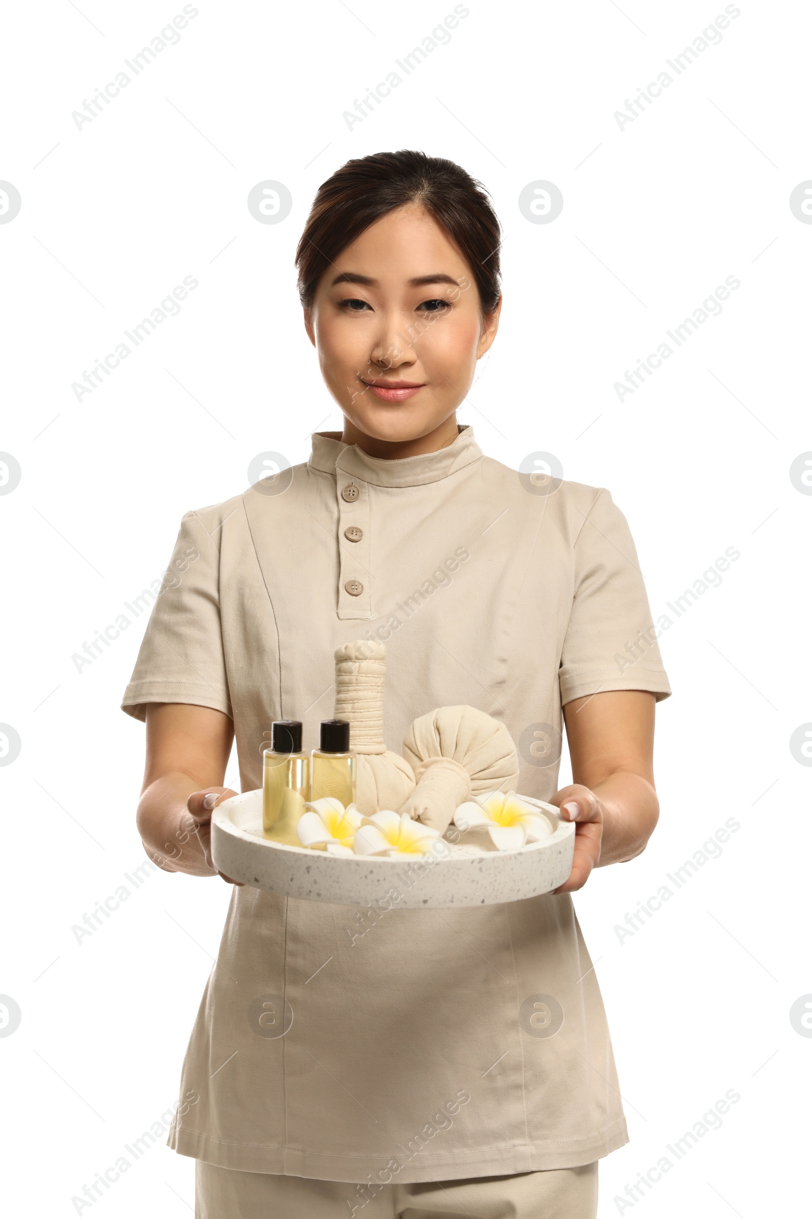 Photo of Professional masseuse in uniform holding tray with spa supplies on white background