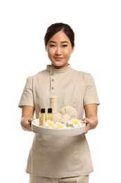 Photo of Professional masseuse in uniform holding tray with spa supplies on white background