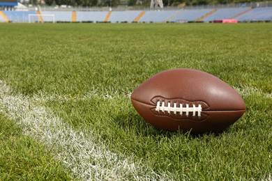 Photo of American football ball on green field grass in stadium