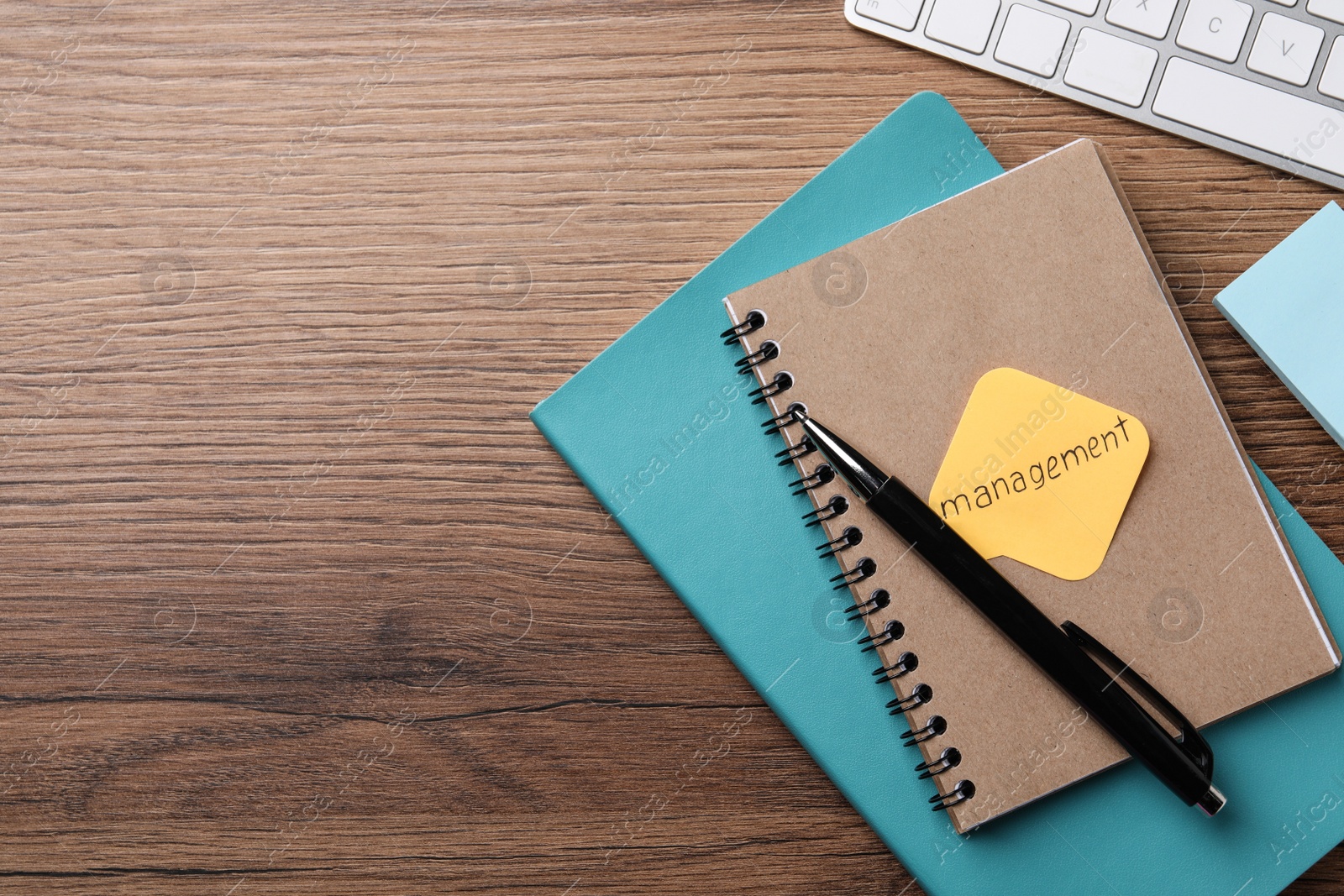 Photo of Paper note with word Management, notebooks and keyboard on wooden table, flat lay. Space for text