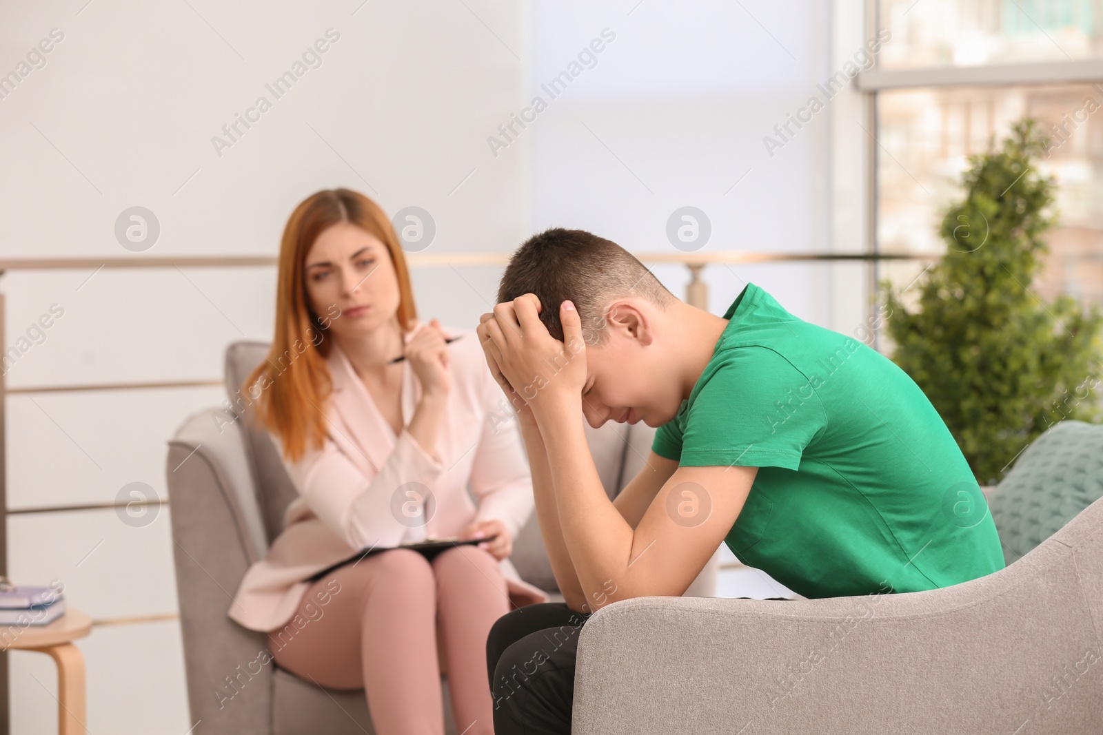 Photo of Young female psychologist working with teenage boy in office