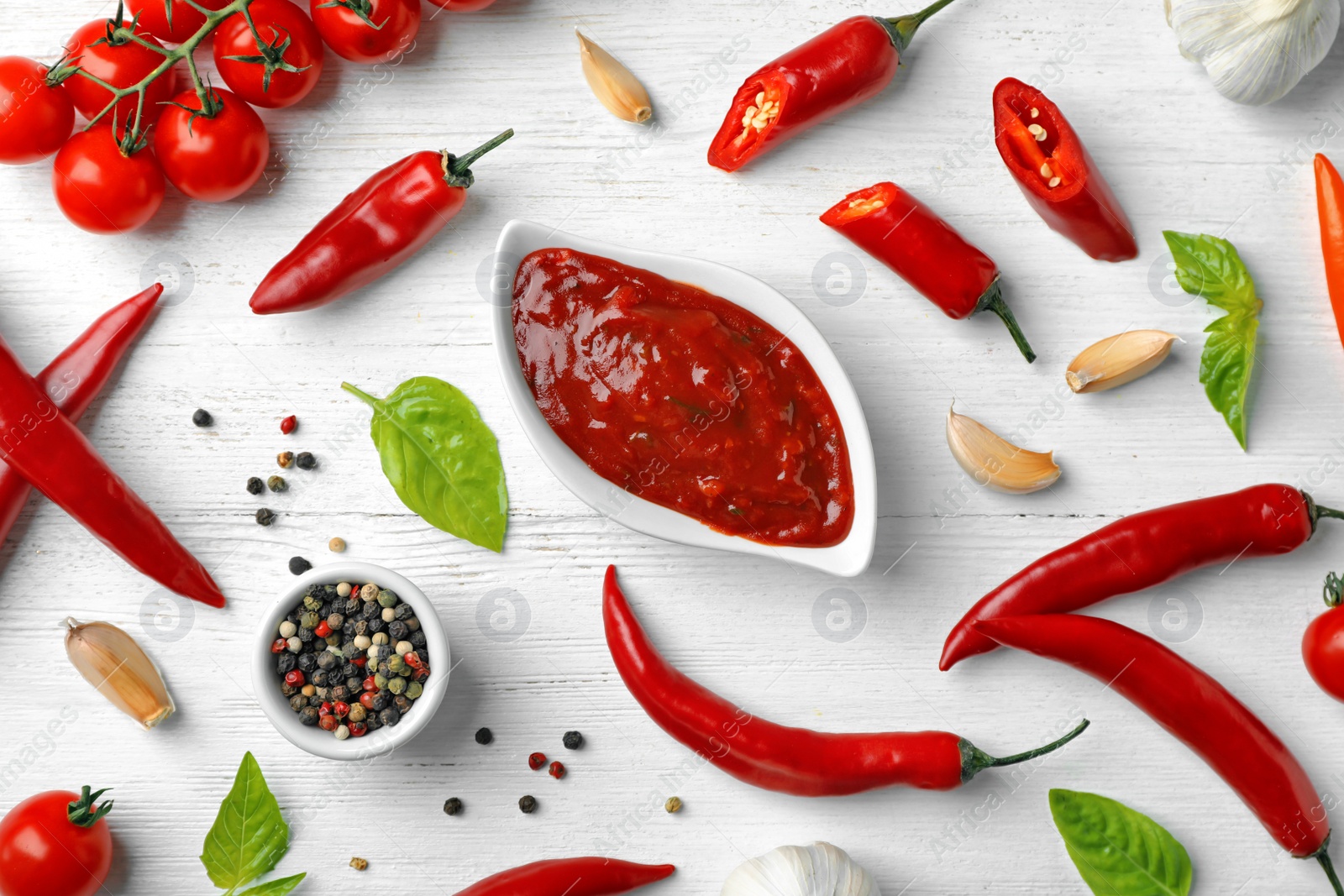 Photo of Flat lay composition with gravy boat of hot chili sauce and different spices on light background