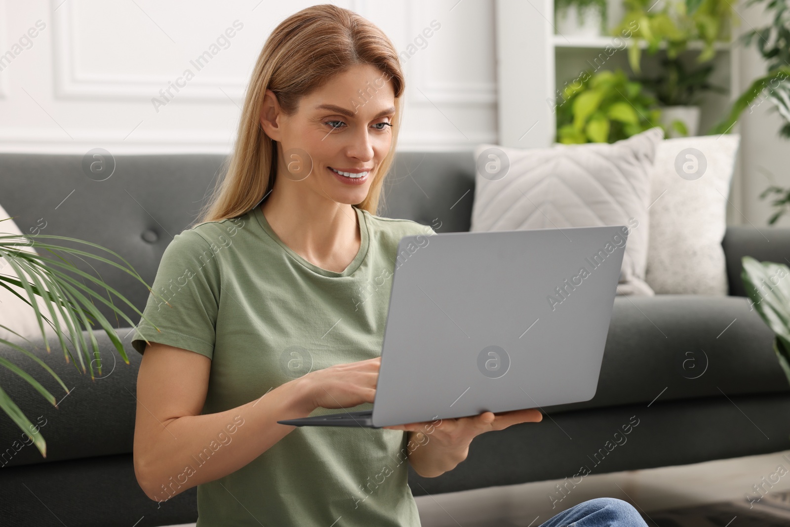 Photo of Woman using laptop in room with beautiful potted houseplants