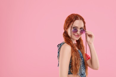 Photo of Stylish young hippie woman in sunglasses on pink background, space for text