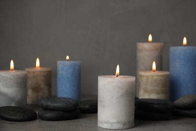 Photo of Burning candles and spa stones on grey table