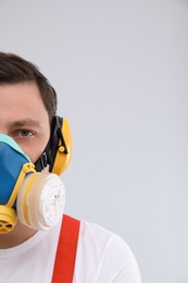 Male industrial worker in uniform on light background, space for text. Safety equipment