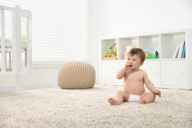 Cute baby boy sitting on carpet at home