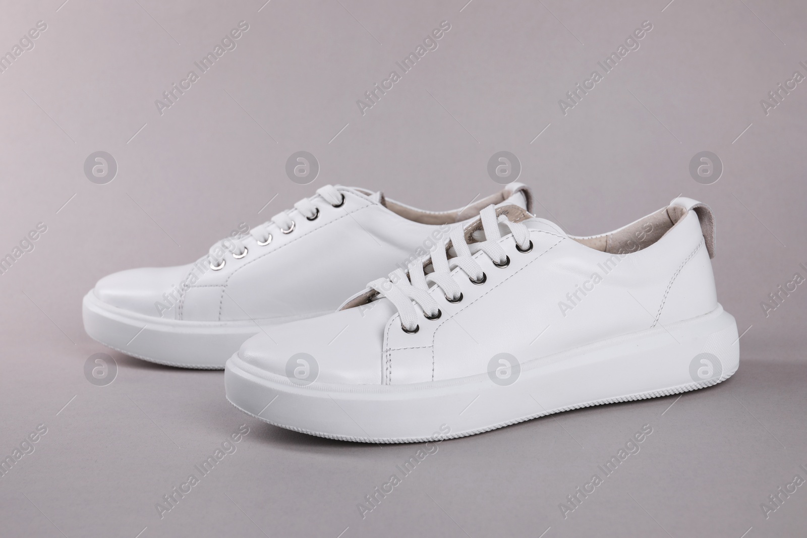 Photo of Pair of stylish white sneakers on grey background