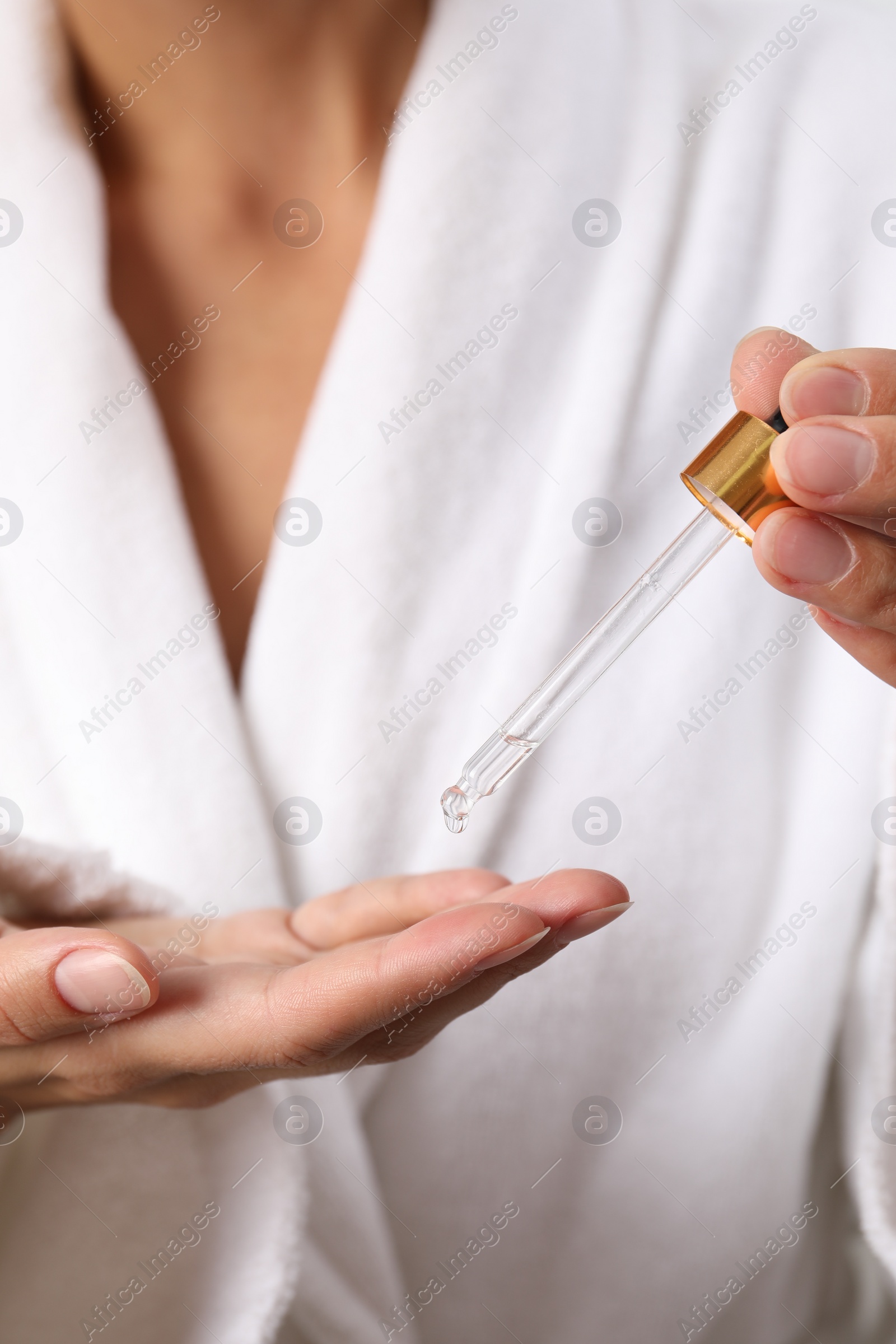 Photo of Woman applying cosmetic serum onto her hand, closeup