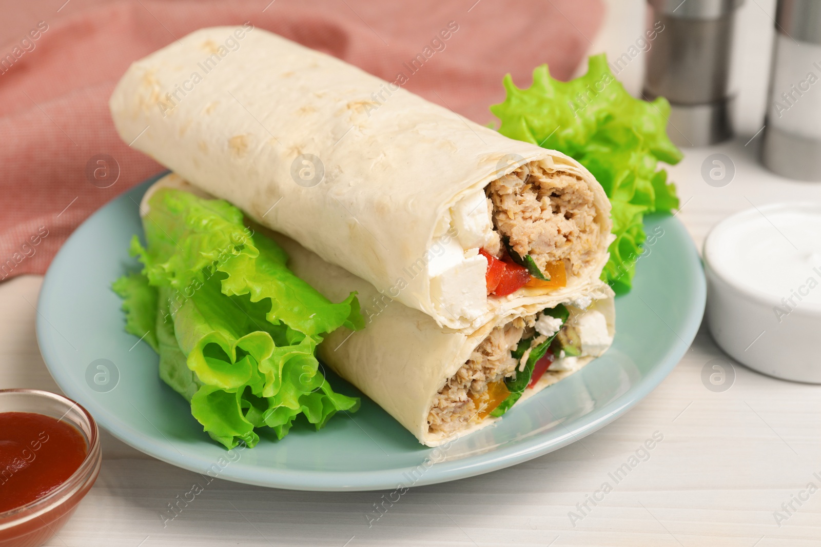 Photo of Delicious tortilla wraps with tuna on white wooden table, closeup