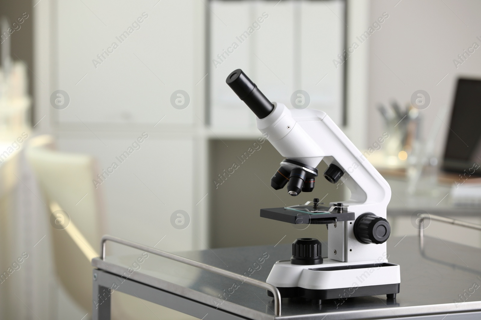 Photo of Modern medical microscope on metal table in laboratory, space for text