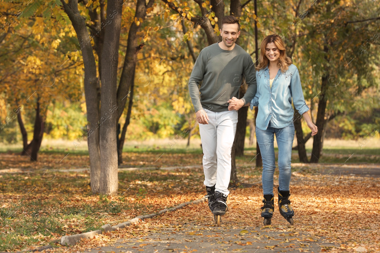 Photo of Young couple roller skating in autumn park