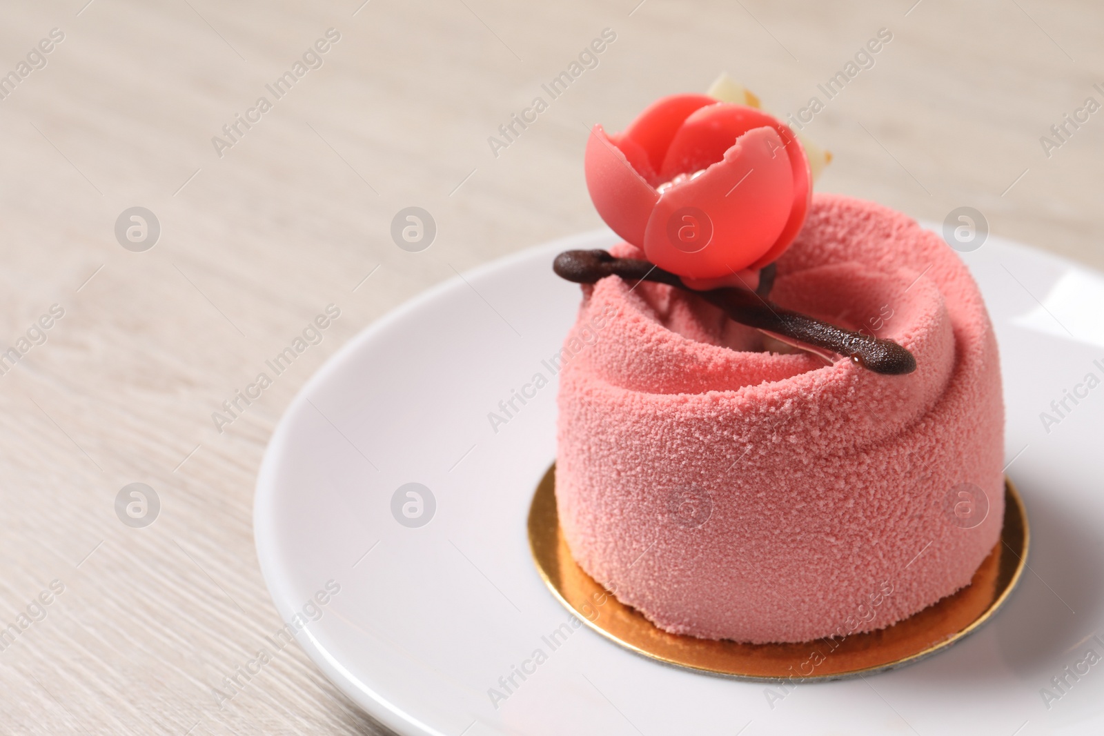 Photo of Delicious mousse cake with floral decor on white wooden table, closeup. Space for text