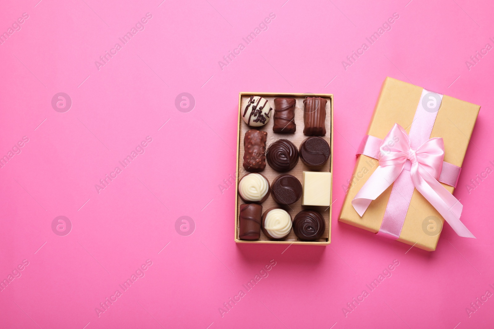 Photo of Open box with delicious chocolate candies on pink background, top view. Space for text