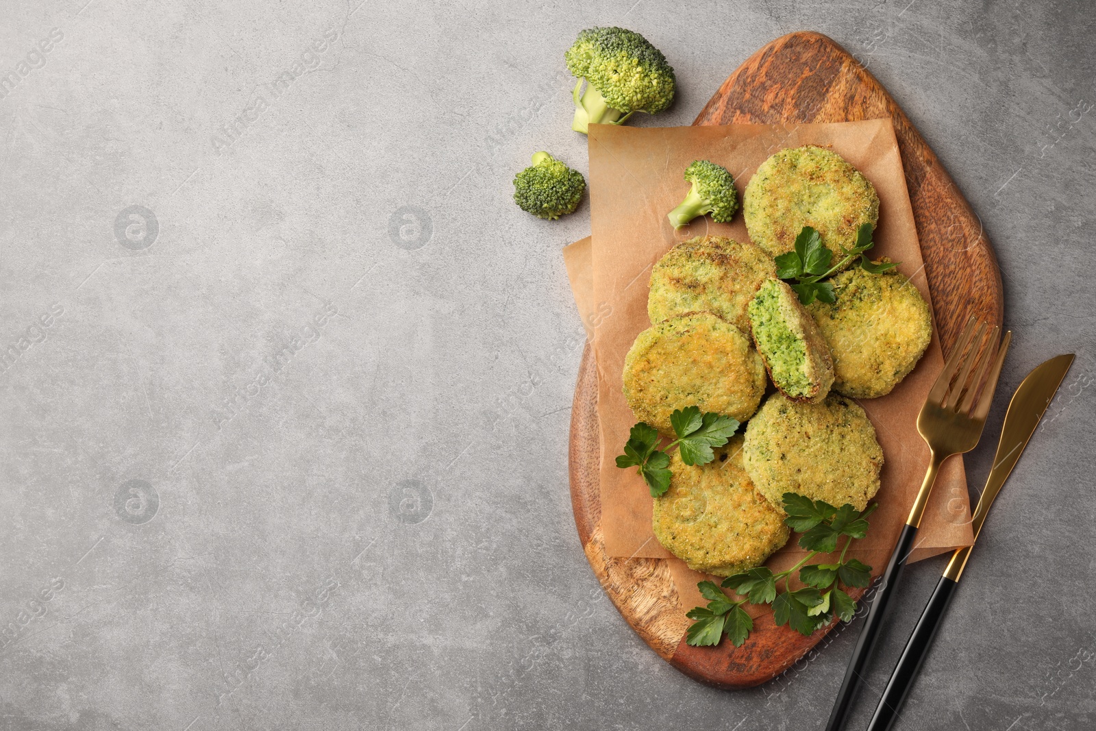 Photo of Delicious vegan cutlets with broccoli, parsley and cutlery on light gray table, flat lay. Space for text