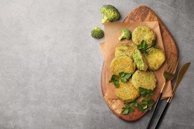 Photo of Delicious vegan cutlets with broccoli, parsley and cutlery on light gray table, flat lay. Space for text