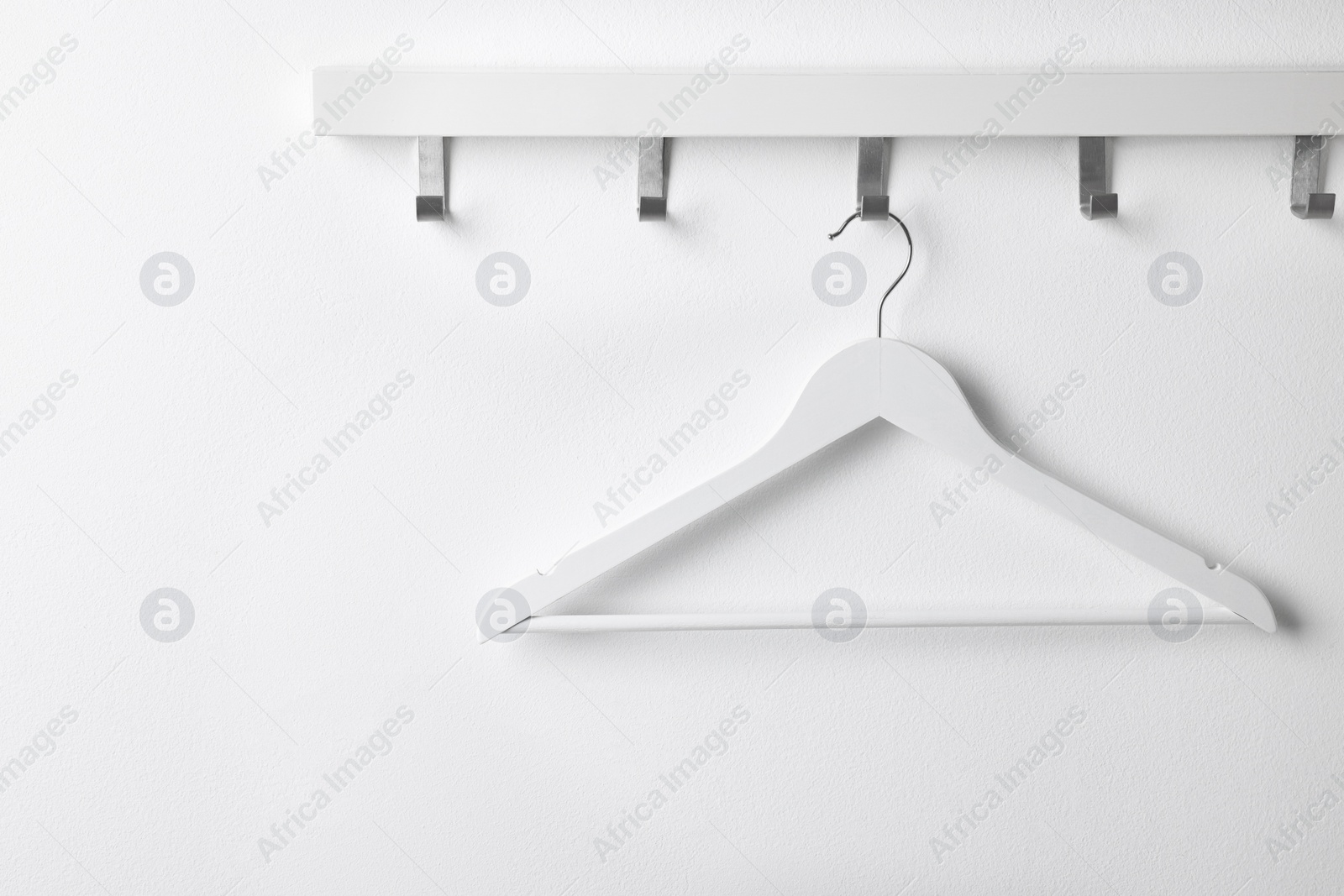 Photo of Rack with empty clothes hanger on white wall