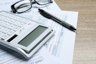 Photo of Calculator, documents and pen on wooden table, closeup. Tax accounting