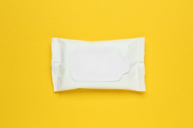 Wet wipes flow pack on yellow background, top view