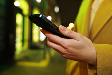 Woman with smartphone on night city street, closeup