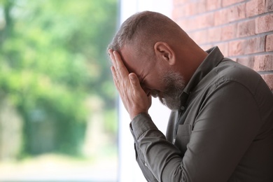 Senior man in state of depression near brick wall