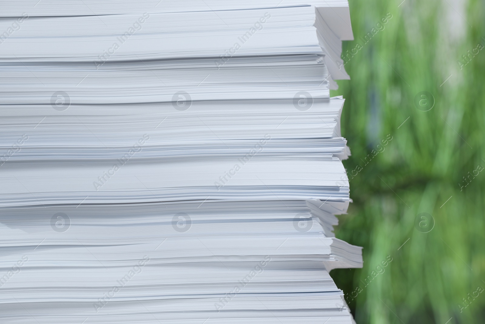 Photo of Stack of paper sheets against blurred background, closeup. Space for text