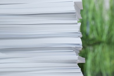 Stack of paper sheets against blurred background, closeup. Space for text