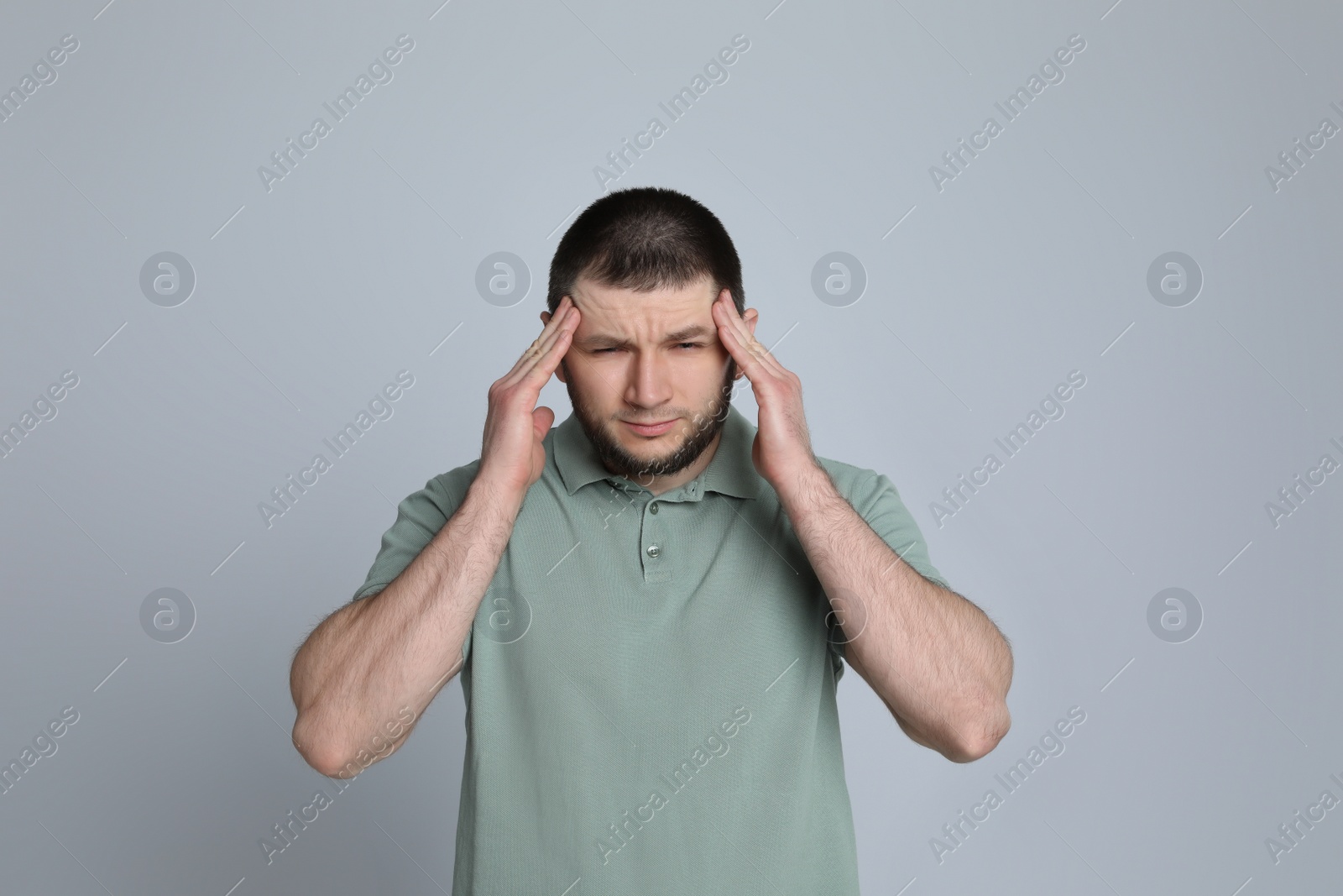 Photo of Man suffering from headache on light grey background