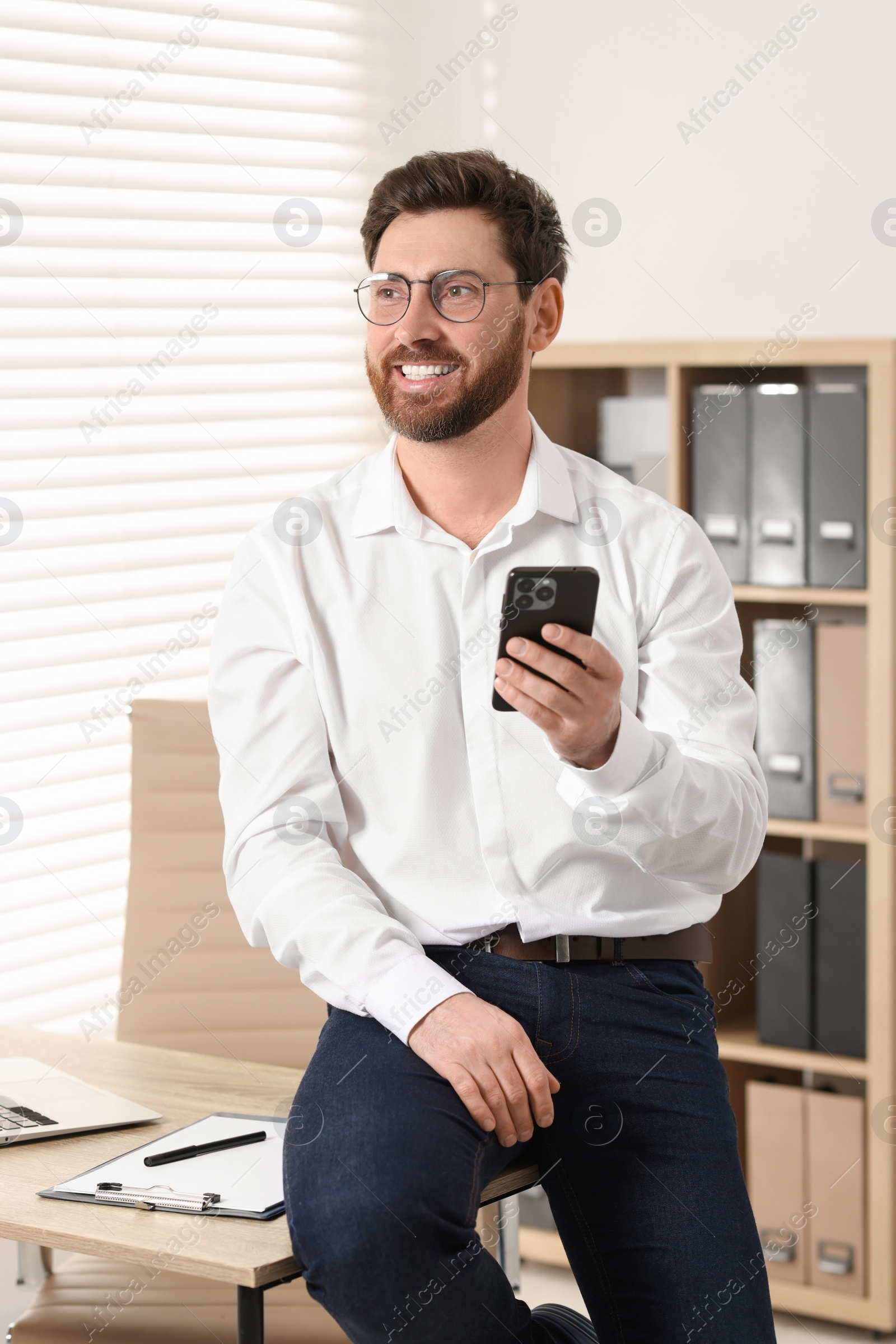 Photo of Portrait of smiling man with smartphone in office