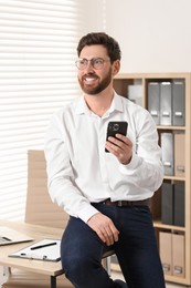 Portrait of smiling man with smartphone in office