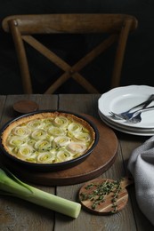 Photo of Tasty leek pie, fresh stalk and thyme on wooden table
