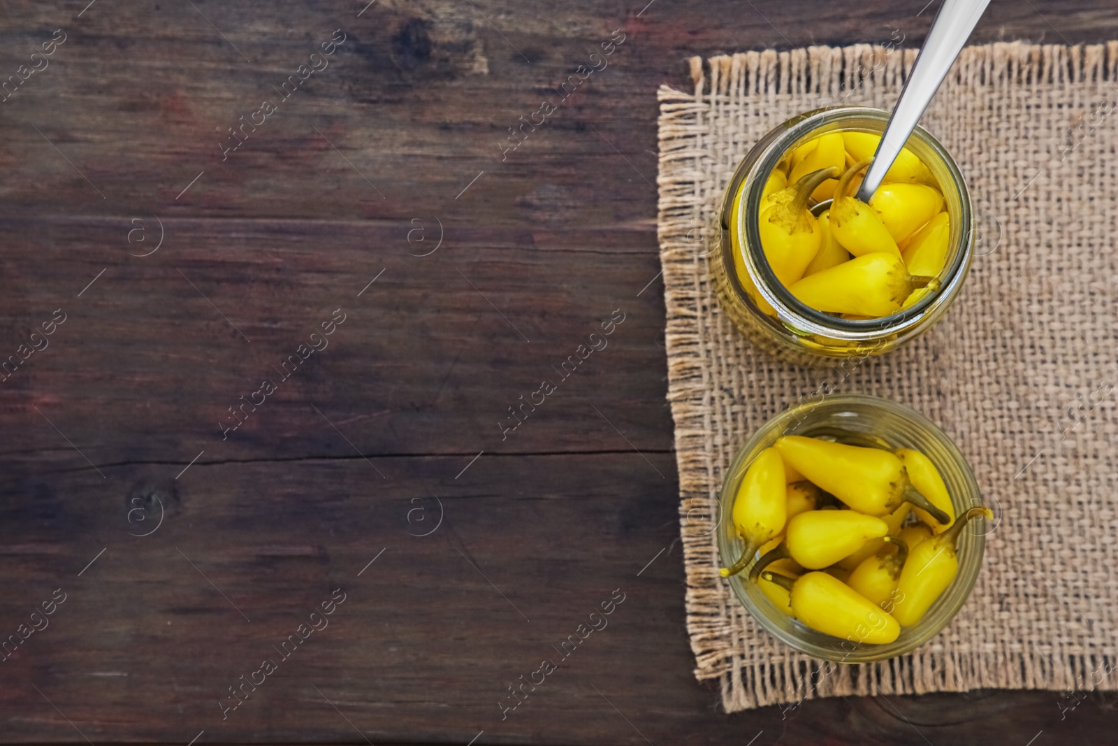 Photo of Pickled yellow jalapeno peppers on wooden table, top view. Space for text