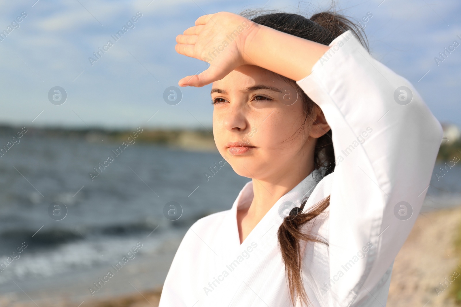 Photo of Cute little girl in kimono practicing karate near river