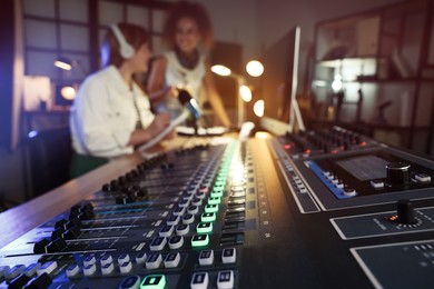 Photo of Women working in modern radio studio, focus on professional mixing console