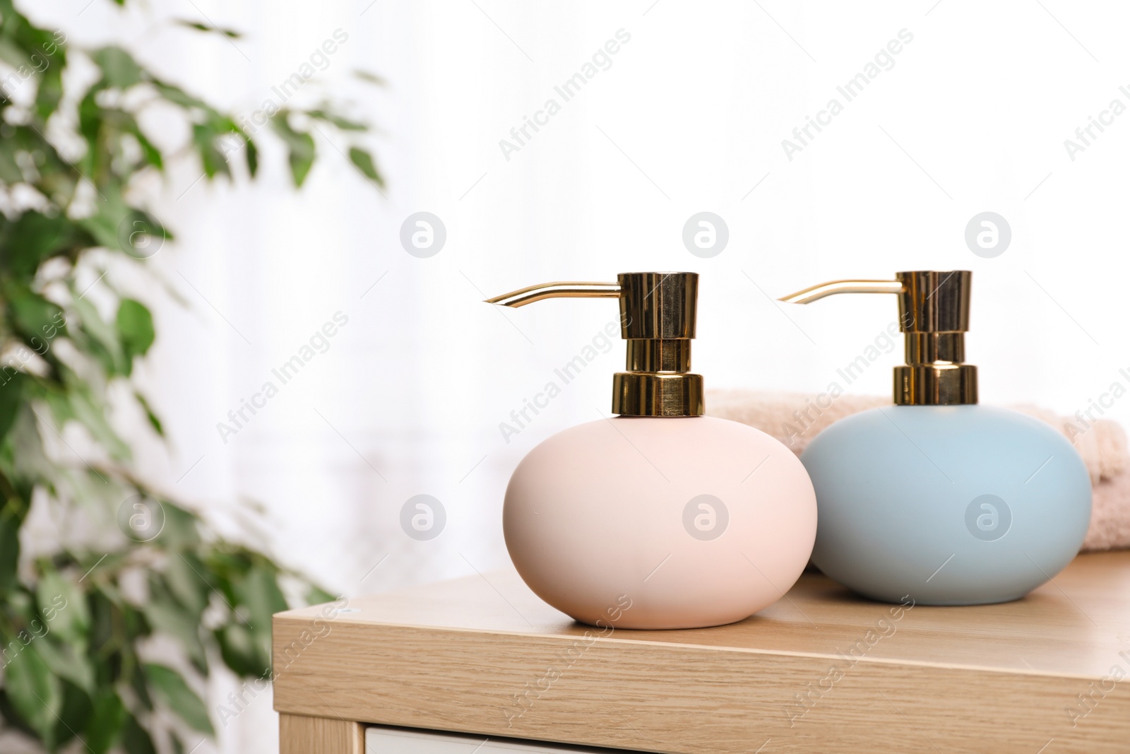 Photo of Stylish soap dispensers on table against blurred background. Space for text