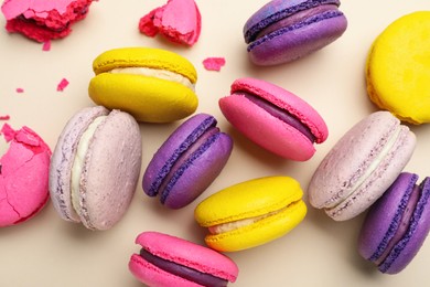 Photo of Delicious colorful macarons on beige background, flat lay