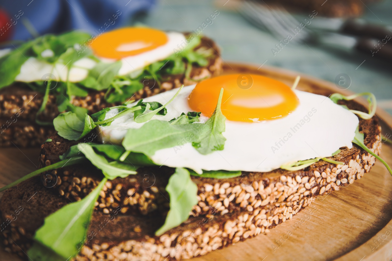 Photo of Delicious sandwiches with arugula and fried egg on wooden board, closeup